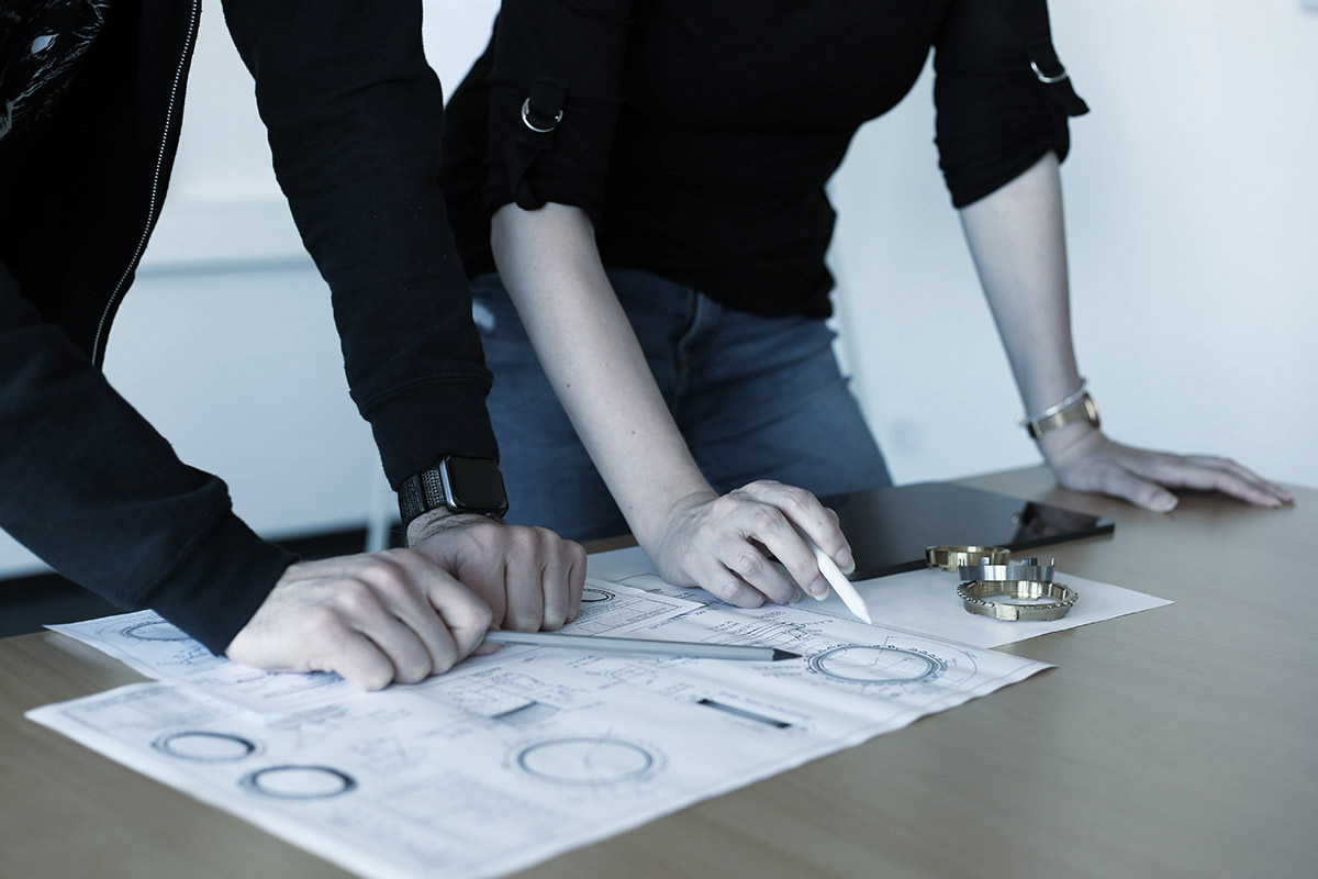 Two persons are looking at technical drawings